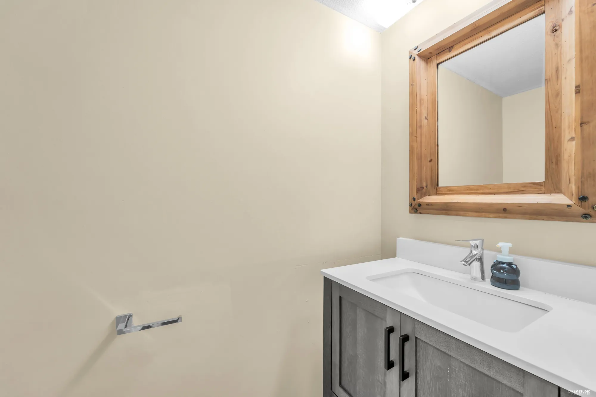 A bathroom vanity in grey with a timber-framed mirror