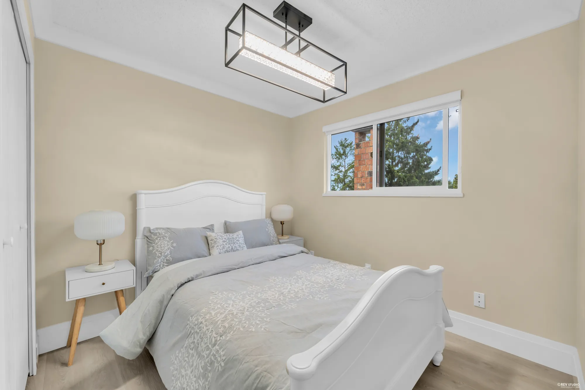 A bedroom with a dressed white bed and a window