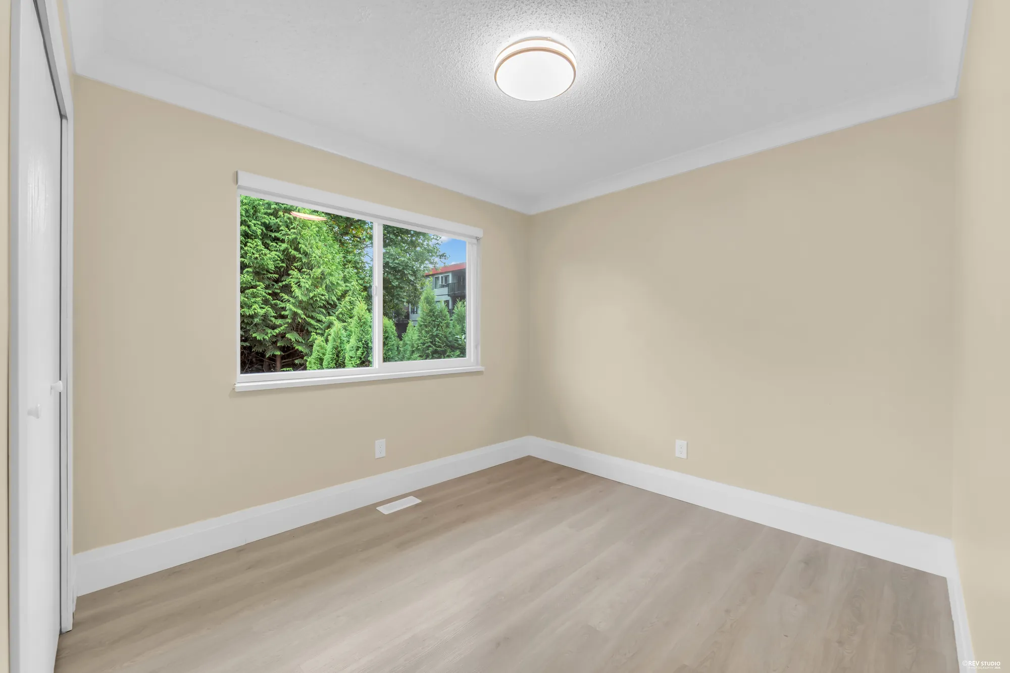 A bedroom, unfurnished, with a window onto the trees