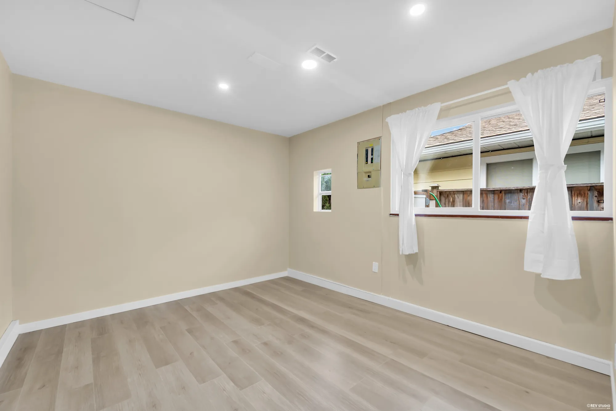The main-floor bedroom, unfurnished, with a window and white curtains