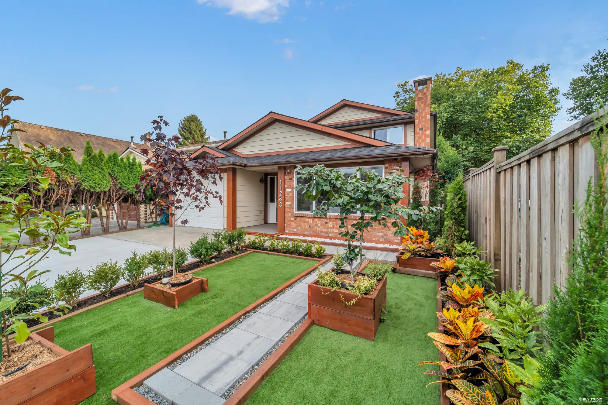 The raised cedar planting beds at the front and a young purple-leafed tree, the house behind