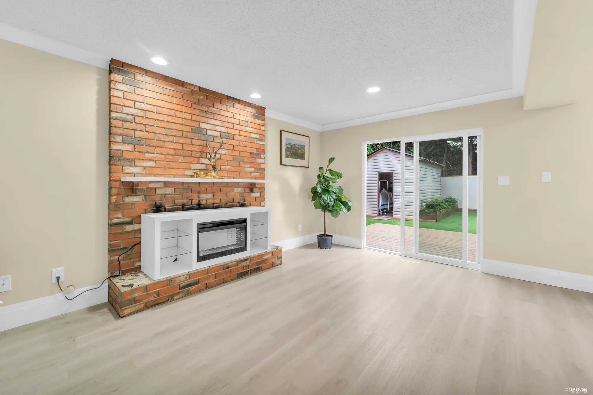 The family room with an exposed brick fireplace and the sliding doors to the deck