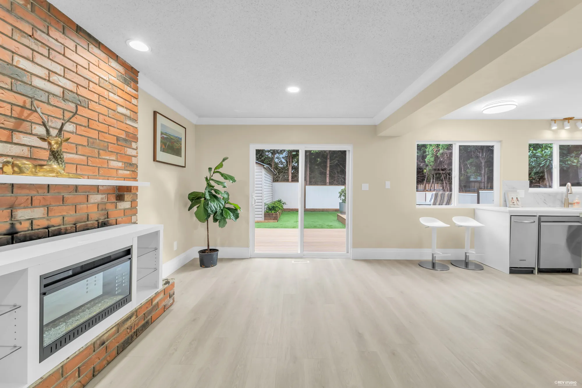 The brick fireplace and the doors to the deck, a plant beside them