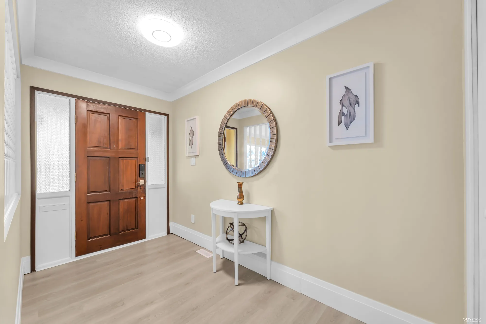 The foyer with the timber front door, a round mirror and a console