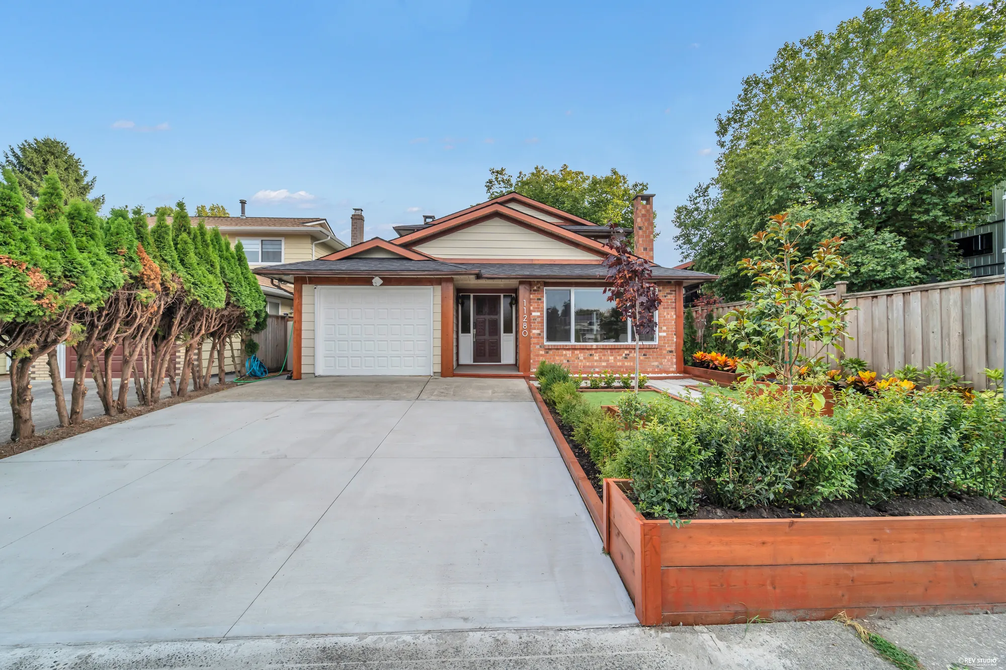 The drive from the sidewalk, the raised beds along its right-hand side and the house at the end