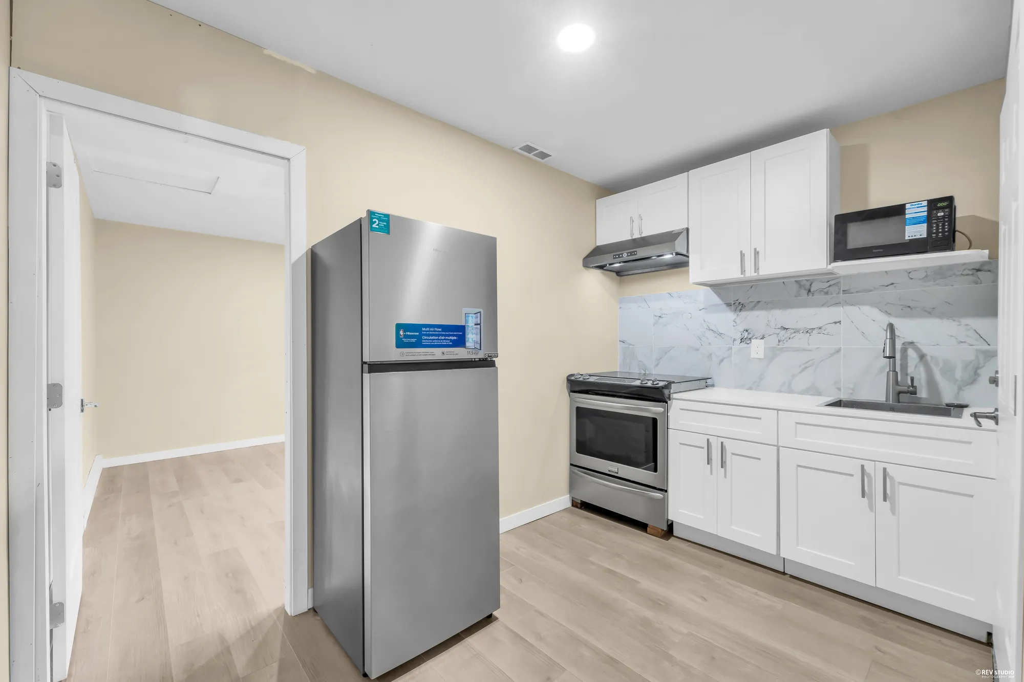 The second kitchen: white cabinets, a stainless range and fridge, and a marbled backsplash