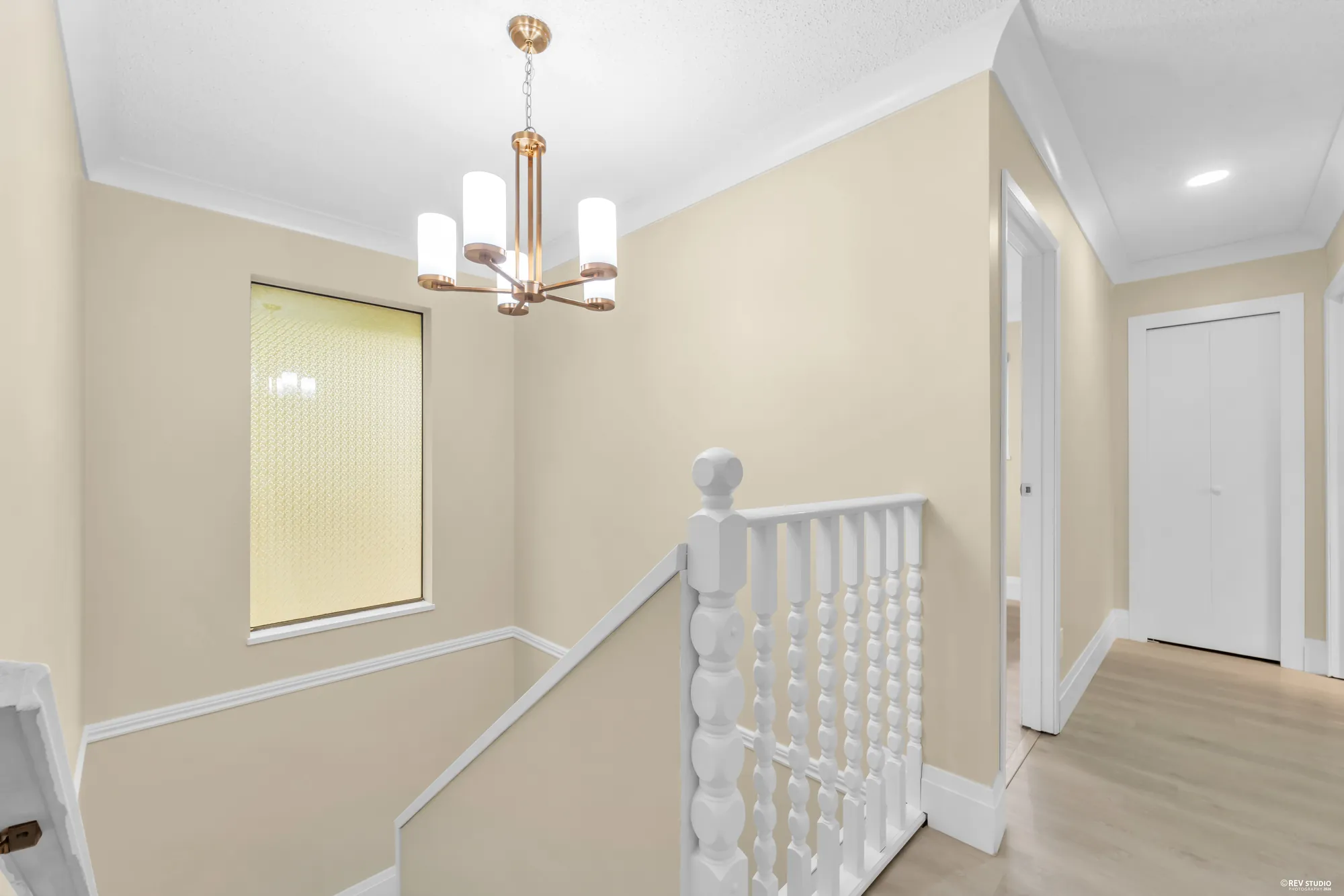 The upstairs landing with a chandelier and the white spindled stair rail
