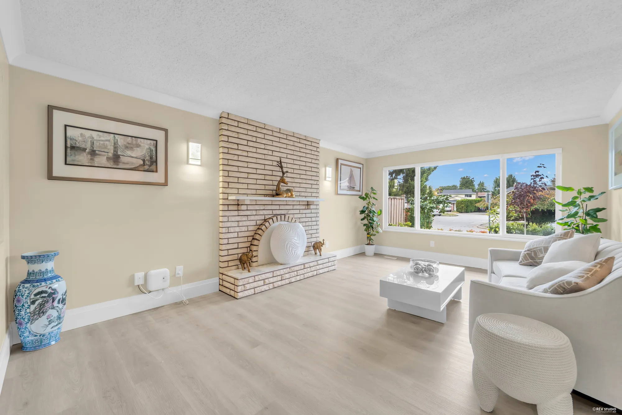 The living room wide, the white-painted brick fireplace with a raised hearth and the window beside it