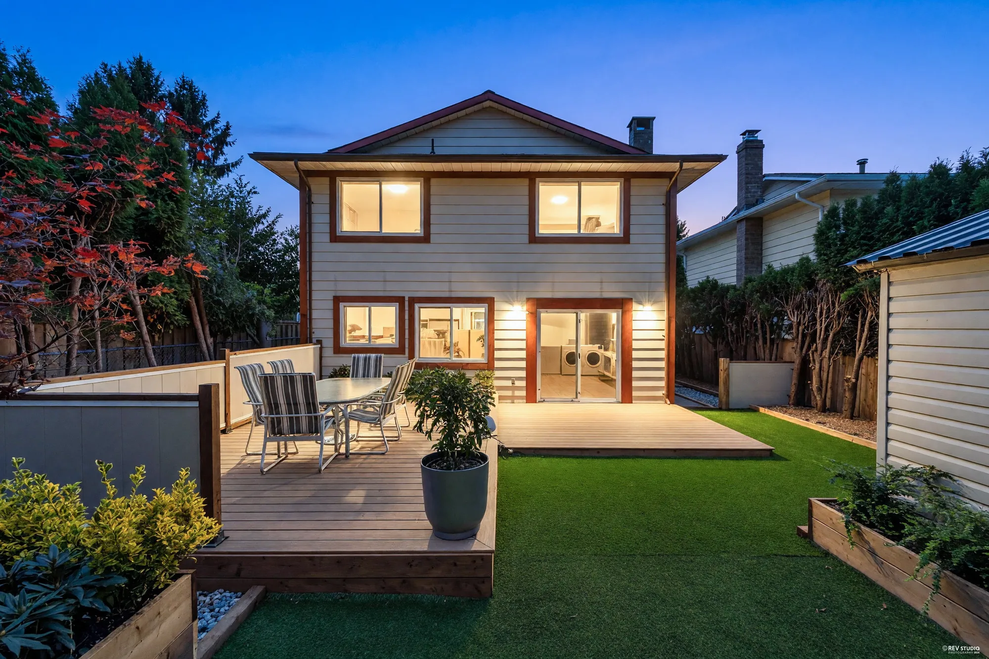 The same view of the back at dusk, the windows and two wall lights by the sliding door lit